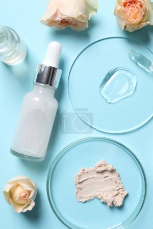 Photo for Bottle of cosmetic serum, flowers and petri dishes with samples on light blue background, flat lay - Royalty Free Image