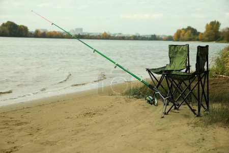 Foto de Sillas plegables y caña de pescar a orillas del río - Imagen libre de derechos