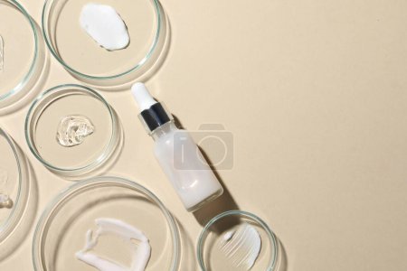Photo for Bottle of cosmetic serum and petri dishes with samples on beige background, flat lay. Space for text - Royalty Free Image