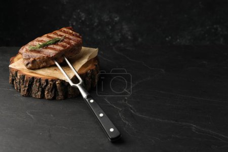 Delicious grilled beef steak served with rosemary on dark gray table, space for text