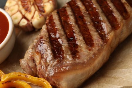 Delicious grilled beef steak with spices on parchment paper, closeup