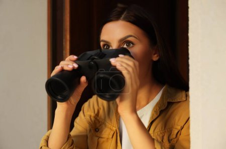 Konzept des Privatlebens. Neugierige junge Frau mit Fernglas spioniert Nachbarn aus