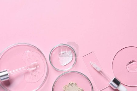 Pipetas, suero cosmético y placas de Petri con muestras sobre fondo rosa, planas. Espacio para texto