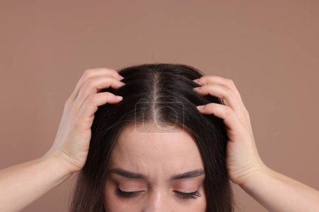 Téléchargez les photos : Femme examinant ses cheveux et son cuir chevelu sur fond beige, gros plan - en image libre de droit
