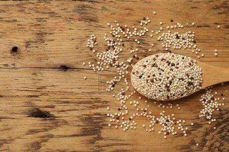 Photo for Spoon with raw quinoa seeds on wooden table, top view. Space for text - Royalty Free Image