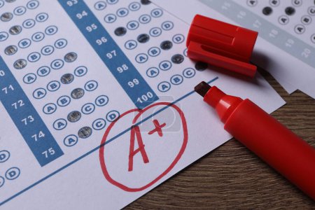 Photo for School grade. Answer sheet with red letter A, plus symbol and marker on wooden table, closeup - Royalty Free Image