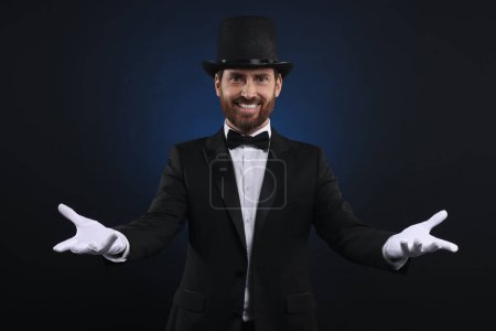 Happy magician in top hat on dark blue background