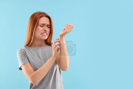 An Allergien leiden. Junge Frau kratzt mit dem Arm auf hellblauem Hintergrund, Raum für Text