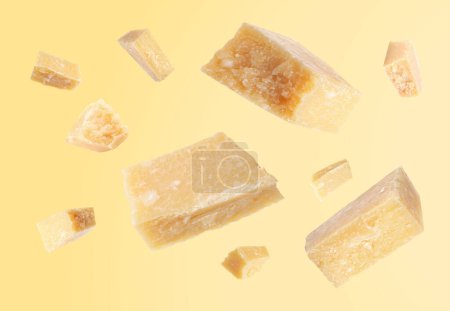 Parmesan cheese in air on pale yellow background