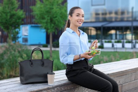 Téléchargez les photos : Femme d'affaires souriante déjeunant pendant la pause en plein air - en image libre de droit