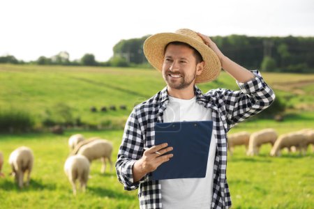 Lächelnder Bauer mit Klemmbrett und Tieren auf der Weide