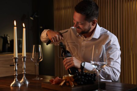 Romantisches Abendessen. Mann öffnet Weinflasche mit Korkenzieher an Tisch im Haus