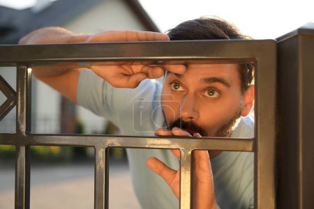 Téléchargez les photos : Concept de vie privée. Homme curieux espionnant les voisins au-dessus de la clôture à l'extérieur - en image libre de droit