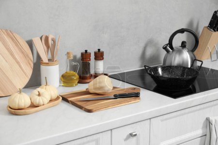 Foto de Tableros de cortar de madera, otros utensilios de cocina y calabazas en encimera blanca en la cocina - Imagen libre de derechos