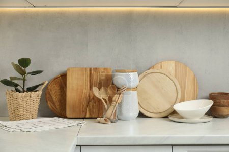 Foto de Diferentes tablas de cortar de madera, otros utensilios de cocina y planta de interior en la encimera blanca en la cocina - Imagen libre de derechos