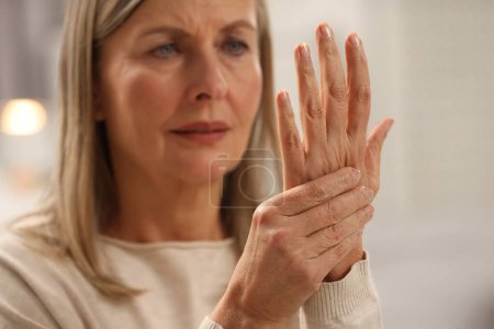Photo for Mature woman suffering from pain in hand on blurred background, selective focus. Rheumatism symptom - Royalty Free Image
