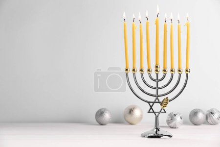 Téléchargez les photos : Hanoukka fête. Menorah avec des bougies allumées et des ornements de vacances sur une table en bois blanc, espace pour le texte - en image libre de droit