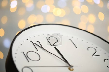 Uhr zeigt fünf Minuten bis Mitternacht auf verschwommenem Hintergrund, Nahaufnahme. Countdown zum neuen Jahr