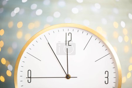 Uhr zeigt fünf Minuten bis Mitternacht auf verschwommenem Hintergrund, Nahaufnahme. Countdown zum neuen Jahr