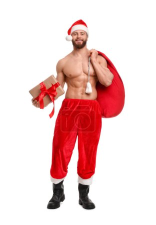 Photo for Attractive young man with muscular body in Santa hat holding bag and Christmas gift box on white background - Royalty Free Image