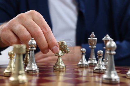 Man moving knight on chessboard, closeup view