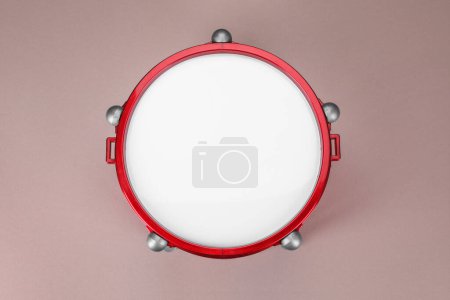 Drum on dusty rose background, top view. Percussion musical instrument