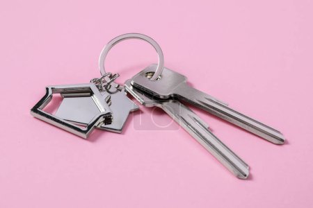 Téléchargez les photos : Clés métalliques avec porte-clés en forme de maisons sur fond rose - en image libre de droit