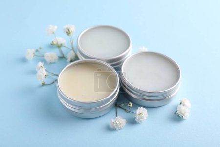 Photo for Different lip balms and gypsophila on light blue background - Royalty Free Image