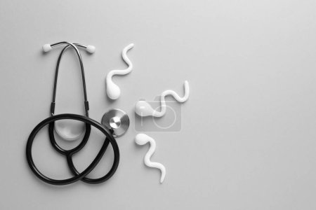 Reproductive medicine. Figures of sperm cells and stethoscope on gray background, flat lay with space for text