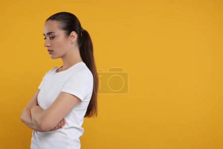 Portrait of resentful woman with crossed arms on orange background, space for text
