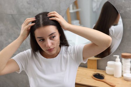 Téléchargez les photos : Femme examinant ses cheveux et son cuir chevelu à la maison. Problème de pellicules - en image libre de droit