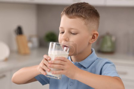 Téléchargez les photos : Mignon garçon boire du lait frais à partir de verre à l'intérieur - en image libre de droit
