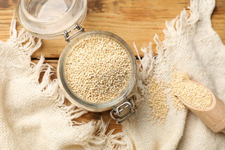 Photo for Dry quinoa seeds and scoop in glass jar on wooden table, top view - Royalty Free Image