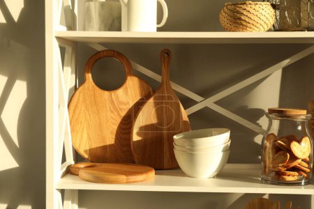 Tableros de madera para cortar, vajilla, utensilios de cocina y galletas palmier francesas en estanterías