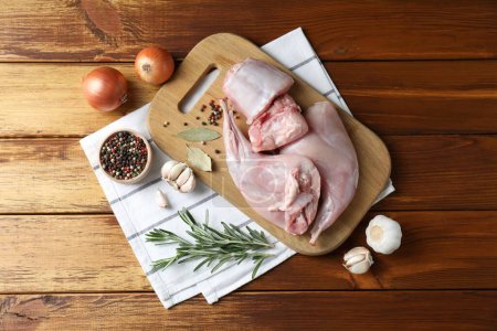 Photo for Fresh raw rabbit meat and spices on wooden table, flat lay - Royalty Free Image