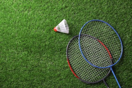 Téléchargez les photos : Deux raquettes de badminton et un volant sur herbe verte, vue du dessus avec espace pour le texte - en image libre de droit