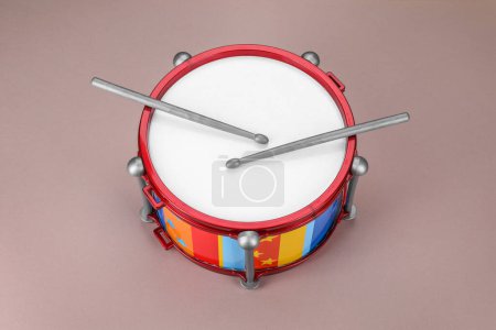 Colorful drum and sticks on dusty rose background. Percussion musical instrument