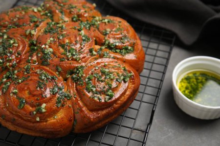 Traditional Ukrainian garlic bread with herbs (Pampushky) on grey table, closeup. Space for text