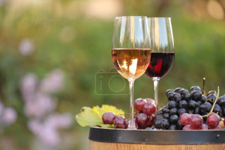 Photo for Delicious wines and ripe grapes on wooden barrel outdoors, space for text - Royalty Free Image