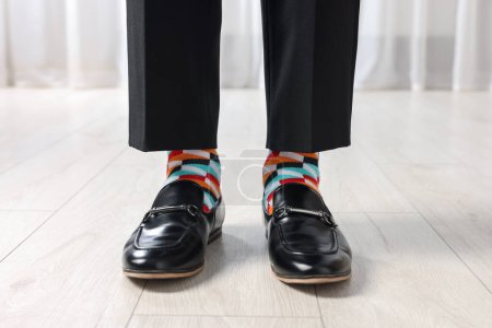 Man in stylish colorful socks, shoes and pants indoors, closeup