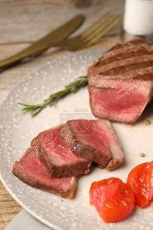 Delicious grilled beef steak with tomatoes on table, closeup