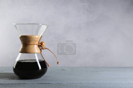 Cafetière chemex en verre avec café goutte à goutte sur table en bois gris. Espace pour le texte