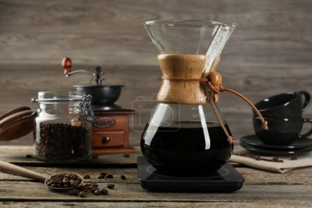 Photo for Glass chemex coffeemaker with coffee and beans on wooden table - Royalty Free Image