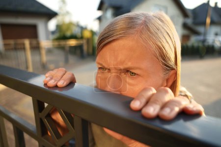 Konzept des Privatlebens. Neugierige Seniorin spioniert Nachbarn über Zaun im Freien aus