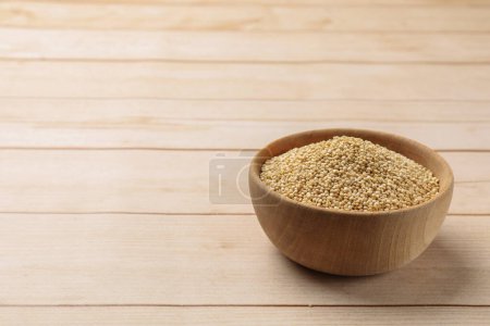 Photo for Raw quinoa in bowl on wooden table, space for text - Royalty Free Image