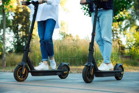 Photo for Couple riding modern electric kick scooters in park, closeup - Royalty Free Image