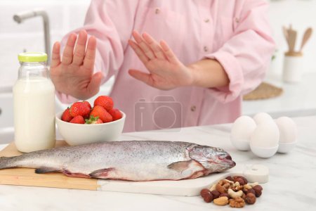 Woman suffering from food allergies refusing eat different fresh products at light table indoors, closeup