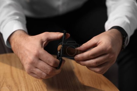 Mann schneidet Zigarrenspitze an Holztisch, Nahaufnahme