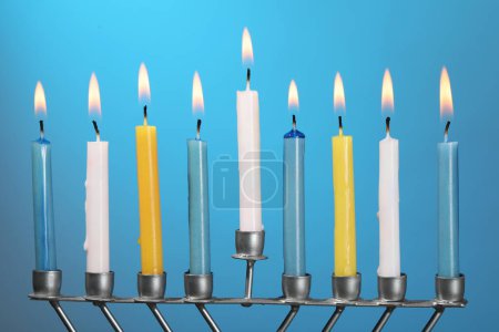 Téléchargez les photos : Hanoukka fête. Menorah avec des bougies allumées sur fond bleu clair, gros plan - en image libre de droit