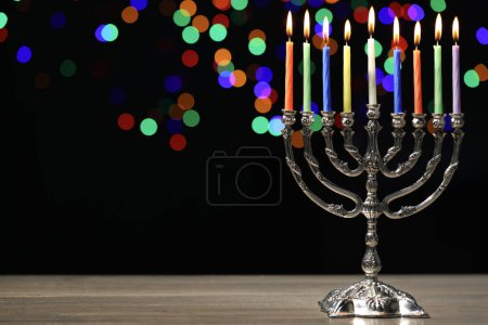 Téléchargez les photos : Hanoukka fête. Menorah avec des bougies allumées sur une table en bois sur fond sombre avec des lumières floues, espace pour le texte - en image libre de droit